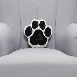 Hook and latch tufted black and white paw shaped pillow on a grey armchair