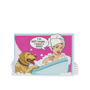 Brunette woman in a deep soaking tub during a bubble bath with her hair in a towel. Her golden retriever is looking at her and has one paw on the edge of the soaking tub. She is saying "I'm NOT single...I have a DOG!" Background is pink and white with white and grey polka dots.